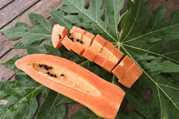 Tranche de papaye fraîche sur fond de feuilles vertes, nature morte — Photo
