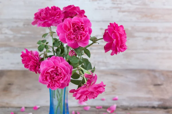 Bodegón con flores rosas rosadas en jarrón azul sobre grunge de madera —  Fotos de Stock