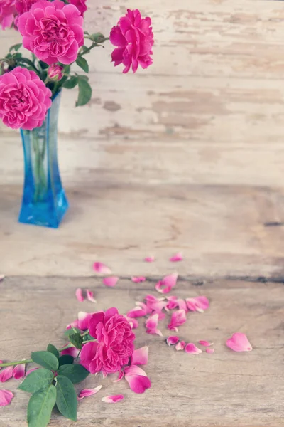 Stilleben med rosa rosor blomma i blå vas på grunge trä — Stockfoto