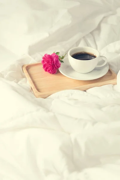 Tasse de café et rose rose fleur avec plateau en bois sur fond de lit — Photo