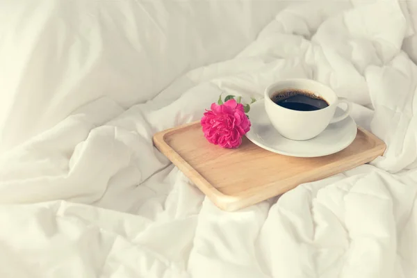 Cup of coffee and pink rose flower with wooden tray on bed backg — Stock Photo, Image