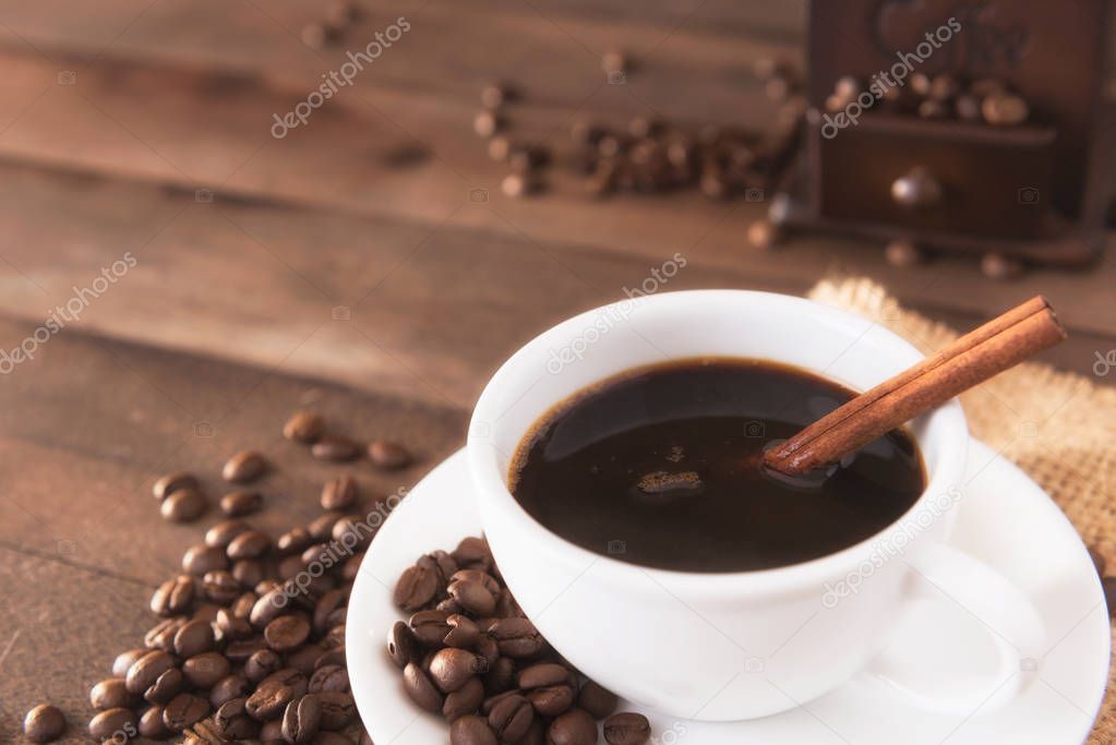 Cup of coffee and sugar stick on old wooden table.