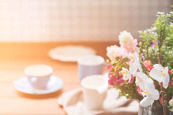 Blaue und weiße Kaffeetassen auf Holztisch mit Blumenstrauß — Stockfoto