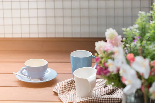 Modré a bílé šálky na kávu na dřevo stůl s dec kytici květin — Stock fotografie