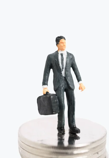 黒のスーツのミニチュア成功ビジネスマンが白い背景で隔離の銀のコインの上に立つ — ストック写真
