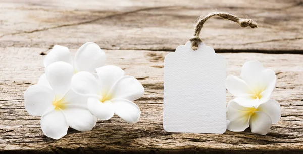 White paper tag label decorate with plumeria flowers on rustic w