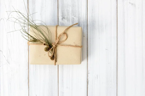 Boże Narodzenie ornamate brązowy prezent pudełko i sosna szyszki świeże zielone biustonosz — Zdjęcie stockowe