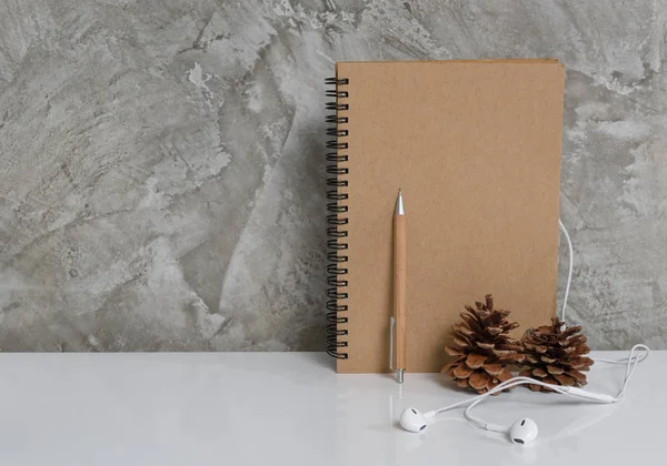 Cuaderno de notas, lápiz, cono de pino y auriculares en el arte de la mesa blanca b — Foto de Stock