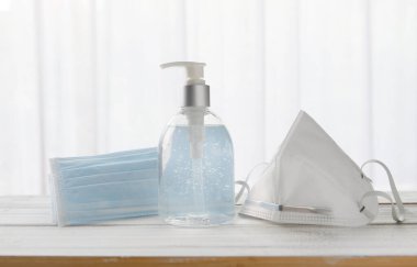 Coronavirus için cerrahi yüz maskeleri ve el dezenfektanı alkol jeli (COVID-19) Ahşap arka planda önleme medikalyonu