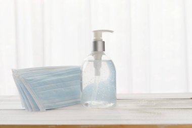 Coronavirus için cerrahi yüz maskeleri ve el dezenfektanı alkol jeli (COVID-19) Ahşap arka planda önleme medikalyonu