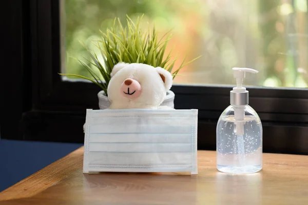 Covid 19家庭检疫时 手部清洁剂 外科口罩 泰迪熊和花盆放在绿色背景的木桌上 — 图库照片