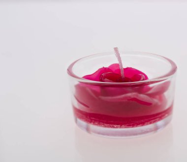 Beyaz arka planda cam içinde güzel kırmızı gül mumu.