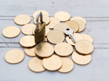 Altın para sikkeleri, ahşap arka planda anahtar ve asma kilit, başarı iş konsepti