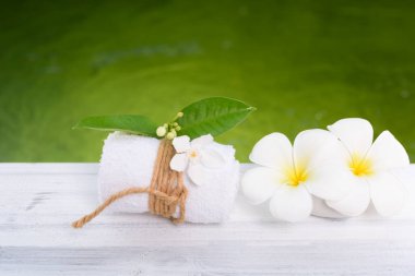 Güzel Frangipani spa çiçeği, beyaz havluyla ahşap masa üzerinde yeşil bilardo arka planı.