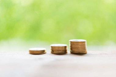 Altın sikkeler ahşap masa üzerinde yeşil bulanık arka plan, tasarruf para konsepti