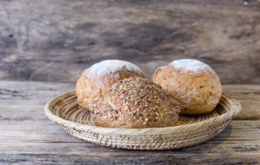 Tahta masanın üstünde bambu sepeti içinde tam buğday ekmeği.