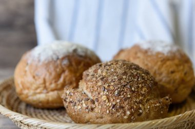 Tahta masanın üstünde bambu sepeti içinde tam buğday ekmeği.