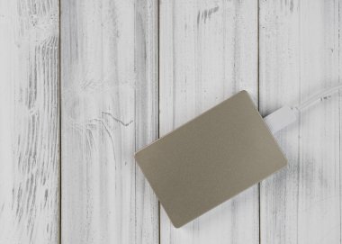 Düz dizayn edilmiş bronz renk harici sabit disk beyaz ahşap arka plan, üst görünüm