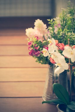 Tahta zeminde bir buket suni çiçek, retro filtre görüntüsü.