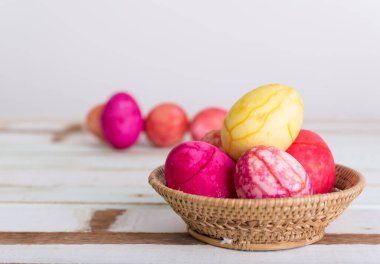 Paskalya yumurtaları sepetin içinde, tahta masanın üstünde.