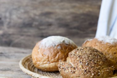 Tahta masanın üstünde bambu sepeti içinde tam buğday ekmeği.