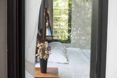 Modern yatak odasının içinde güzel kurumuş çiçek buketi, seçici bir odak noktası.