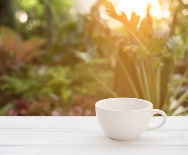 緑の庭の背景を持つ朝の太陽の光でコーヒーカップ — ストック写真