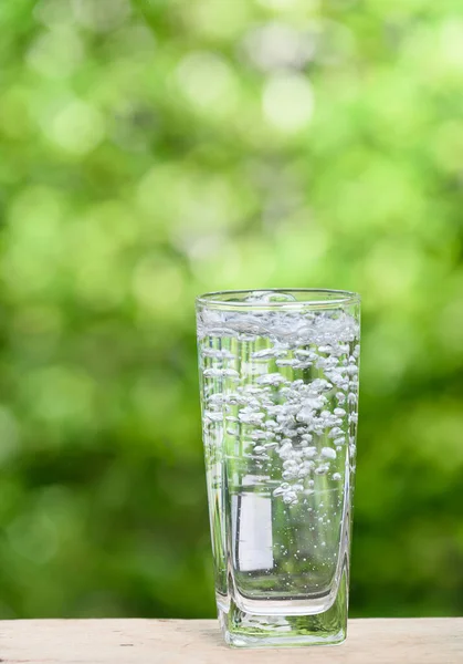 Bicchiere Acqua Spruzzata Sul Tavolo Legno Con Sfondo Verde Natura — Foto Stock