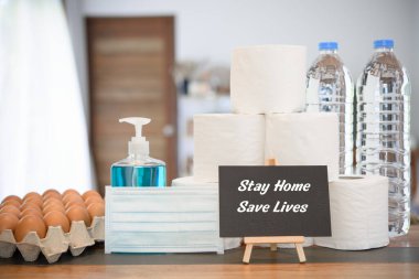 Taze yumurta, el jeli, doku rulosu, içme suyu şişesi ve oturma odasındaki kara tahta tabelasıyla korunan Coronavirus veya COVID-19 nedeniyle ev karantinası