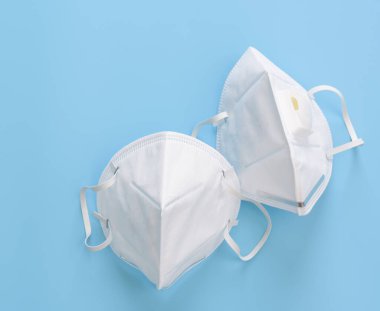 Mavi arka planda bulunan Corona virüsüne karşı mikrop koruması takmak için cerrahi maskeler.