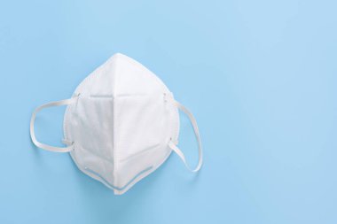 Korona virüsünden korunmak için cerrahi maske. Yumuşak mavi arka plan, üst görünüm.