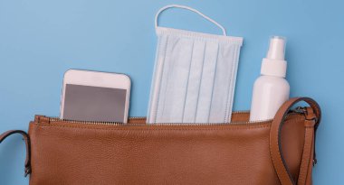 Cerrahi maskeli kadın deri çanta, sprey alkol, el jeli ve cep telefonu hijyen, temizlik ve Covid-19 'dan koruma amaçlı. Coronavirus, üst görünüm