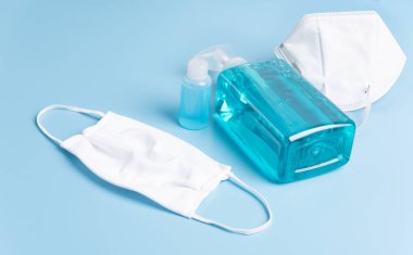 Mikrop koruması ve jel alkolü veya el dezenfektanı şişesi takmak için beyaz maske. Mavi arka plandaki Corona virüsünden korunmak için el yıkama spreyi.