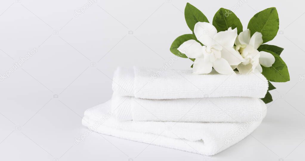 Spa and health care concepts setup with stack of white towels  and tropical Gardenia flowers on white background