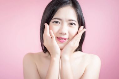 Pembe arka plan üzerinde yukarı doğru izole uzun saçlı Asyalı genç güzel kadın noktası parmak. doğal makyaj, Spa tedavisi, Cilt Bakımı, kozmetik ve plastik cerrahi kavramı.