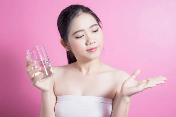 Healthy asian young beautiful woman drinking water, beauty face natural makeup, isolated over pink background. Stock Photo
