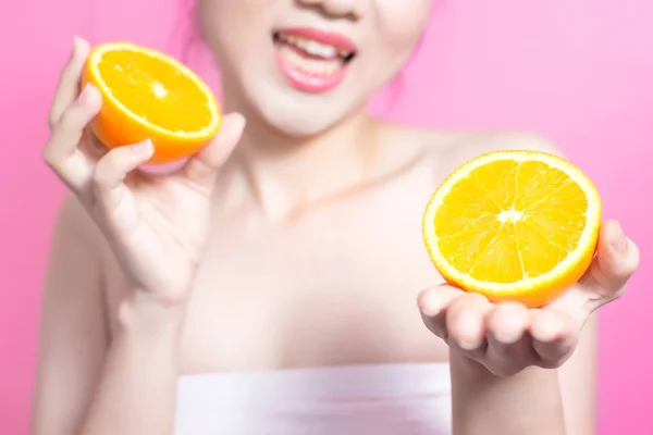 Asian woman with orange concept. She smiling and holding orange. Beauty face and natural makeup. Isolated over pink background. Stock Image