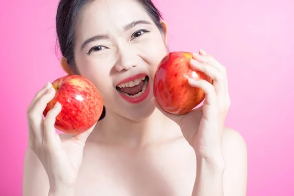 Asian woman with apple concept. She smiling and holding apple. Beauty face and natural makeup. Isolated over pink background. Royalty Free Stock Photos