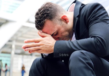 Yürüyen caddede oturan iş adamı ve hüzün.