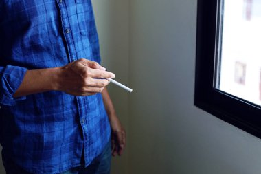 Eli yatak odasında sigara içen adam..