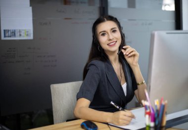 Güzel resepsiyon merkezindeki kadın telefonda müşteriyle konuşuyor ve konuşuyor..
