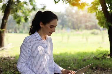 Güzel kız gülümsemesi portresi ve uzun bir tatil haftasonu parkında iş için dizüstü bilgisayar arıyor..