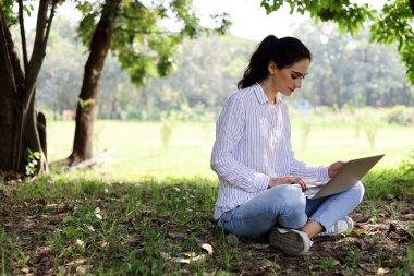 Güzel kız gülümsemesi portresi ve uzun bir tatil haftasonu parkında iş için dizüstü bilgisayar arıyor..