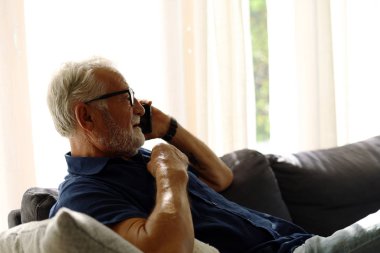 Son sınıf öğrencisi evde yalnız oturuyor ve akıllı telefondan oyun oynuyor..