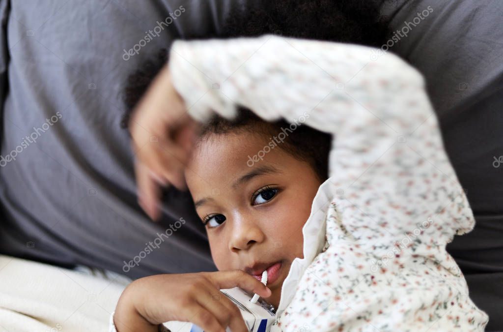 Beautiful African american girl kid smile portrait and drinking milk on bed.
