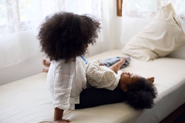 İki Afrikalı kız kardeş tatillerde yatak odasında eğleniyor ve birbirlerine sataşıyorlar..