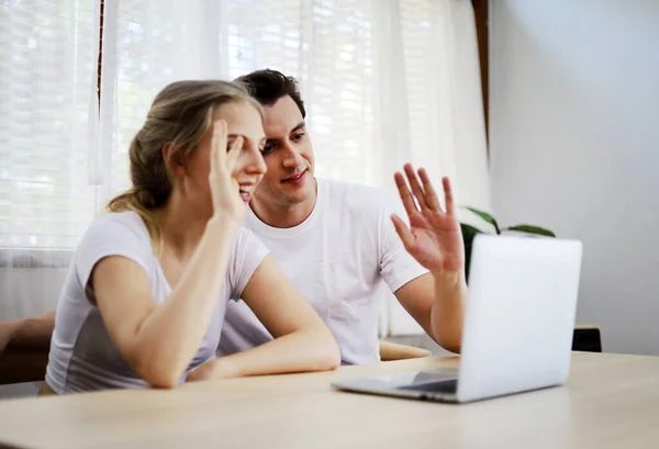 幸せなカップル恋人話と手で手を振ってビデオ会議でラップトップとオンラインで連絡先調査のために自宅で — ストック写真
