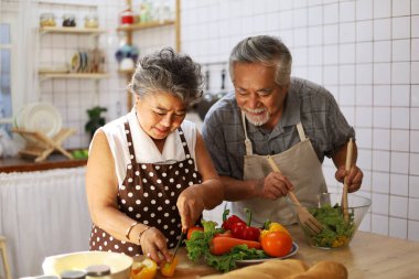 Mutlu, yaşlı bir çift evde çalışmak için sağlıklı yiyeceklerle mutfakta eğleniyor. COVID-19