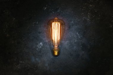 Eskimiş bir ampul, pürüzsüz arka planda sarı parlıyor.. 