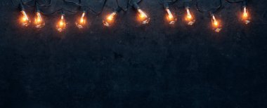Koyu ve kirli arka planda parlayan sicim lambaları sırası.